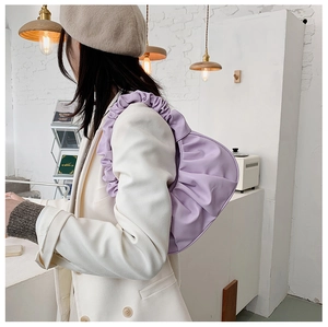 Vista laterale di una borsa a nuvola plissettata viola chiaro indossata da una modella