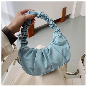 Close-up of light blue pleated cloud bag with scrunchie handle held by a model