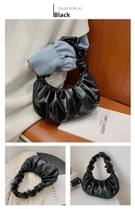 Macro detail of black pleated leather cloud bag showing soft texture and handle