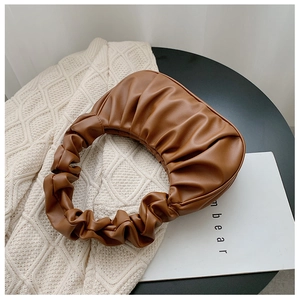 Close-up of caramel pleated cloud bag featuring textured vegan leather and ruched handle