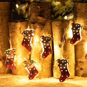 LED Christmas tree lights with red stockings and bear ornaments on wood log background