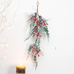 Christmas wall hanging with green pine needles, red berries, pine cones and snow frost