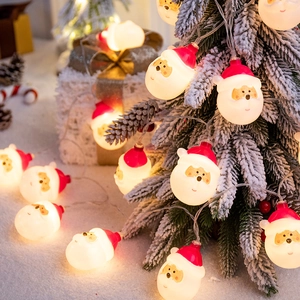 Warm white LED Christmas string lights with Santa Claus heads on a snowy festive tree