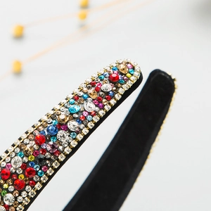 Macro di strass colorati e perline su un'ampia fascia per capelli in tessuto nero
