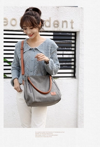 Detail of grey canvas tote with brown leather handles and adjustable shoulder strap