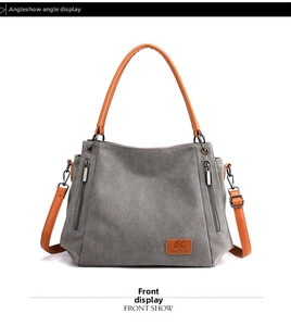 Front view of grey canvas shoulder bag featuring brown straps and vertical zippers