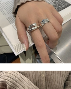 Detail of silver irregular twisted and geometric folding rings worn on fingers over a book