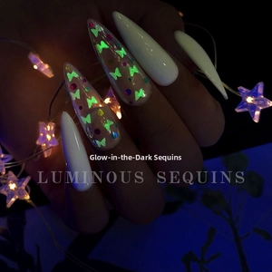 Luminous nail sequins with butterfly shapes glowing green in a dark environment
