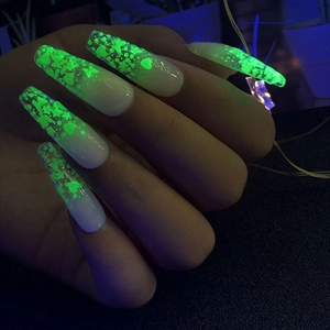 Detail showing long square luminous nail art with glow-in-the-dark stars and heart sequins