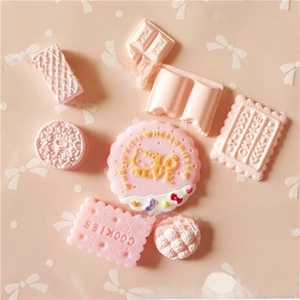 Flat lay of pink resin chocolate and cookie charms for DIY cream phone case crafting