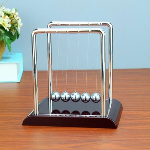 Detailed view of the Newton's cradle with five metal balls on a dark wood base
