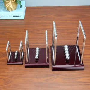 Three Newton's cradles in different sizes featuring metal frames and dark wooden bases