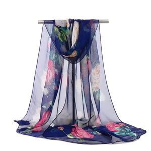 Detailed view of lightweight navy blue floral scarf hanging on a metal rack over white background