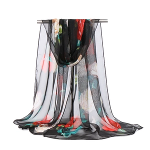 Detail shot of sheer black georgette fabric with vibrant red and white floral patterns