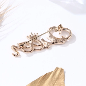 Vue détaillée de la broche dorée Queen avec détails de couronne et silhouette de chat