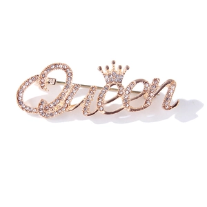 Gros plan sur la broche Queen dorée avec strass scintillants et détail de couronne
