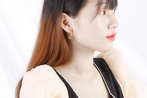 Gros plan d'un mannequin portant d'élégantes boucles d'oreilles nœud dorées au fini poli