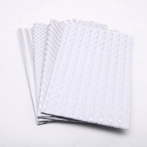 Folded silver and white tissue paper with stars, dots, and stripes for gift wrapping