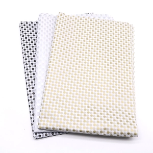 Close-up of folded polka dot wrapping paper in gold, silver, and black metallic foil finish