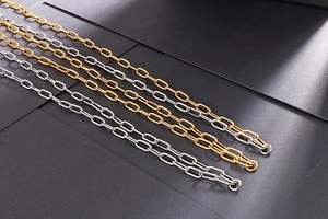 Close-up of gold and silver chunky double-layer military dog tag necklaces on a textured surface