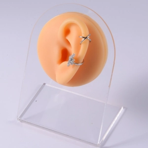 Detailed close-up of silver star and cross ear cuffs on a silicone ear model display