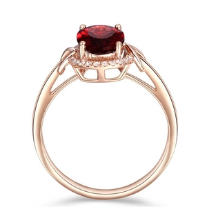 Detailed view of 18k rose gold ring with a large round red gemstone and halo setting