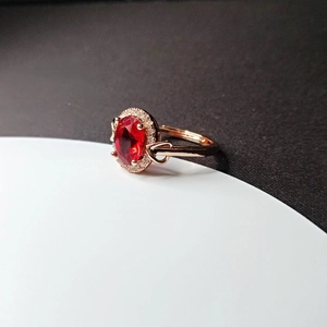 Detail of rose gold plated ring featuring oval red ruby and adjustable heart band