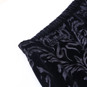 Detailed close-up of black velvet flare pants featuring embossed floral textures and elastic waist