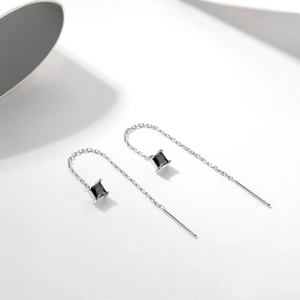 Detailed view of silver box chain earrings featuring black square-cut gemstones