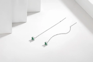 Detailed macro shot of S925 silver drop earrings featuring square green gemstones