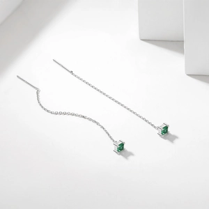 Macro detail of S925 silver threader earrings with square emerald-green stones