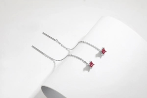 Macro shot of silver S925 threader earrings featuring red square-cut zircon crystals