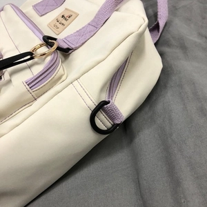 Detailed close-up of canvas bag side with purple strap, D-ring, and reinforced stitching