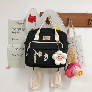 Detail of black canvas bag with cute embroidery and a plush sunflower charm decoration
