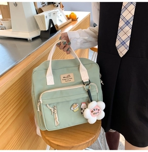 Detail of light green canvas crossbody bag with cute flower plush charm and pins