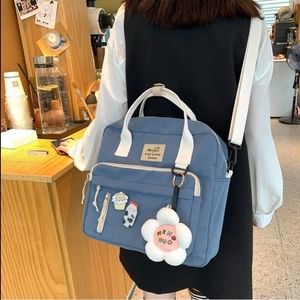 Blue canvas messenger bag with plush flower charm and adjustable straps for casual wear