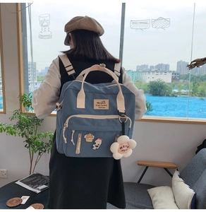 Blue canvas backpack featuring cream handles, floral pendant, and cute pins decoration