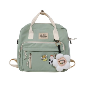 Detail of light green canvas backpack with plush flower pendant and cute decorative pins