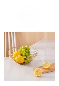 Detail eines goldenen Draht-Obstkorbs mit Trauben und Zitronen auf Marmortisch