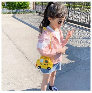 Outdoor shot of a cute yellow car-shaped shoulder bag for kids with POLICE detail