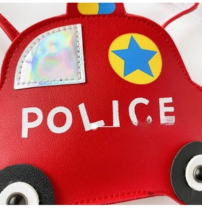 Detail of red police car crossbody bag featuring PU leather texture and holographic window