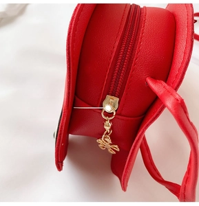 Close-up of red PU leather bag featuring a custom golden butterfly zipper pull detail