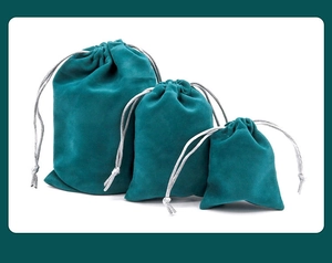 Three sizes of dark green velvet drawstring pouches with silver braided cords for jewelry