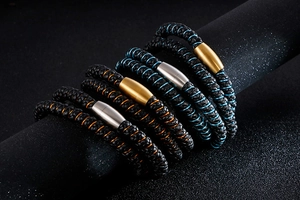 Détail de bracelets en cuir tressé avec coutures colorées et fermoirs magnétiques