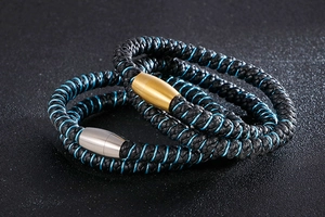 Détail d'un bracelet en cuir noir tressé avec accents bleus et fermoir magnétique en métal