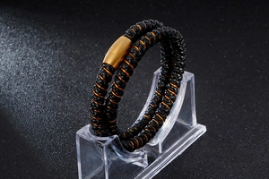 Détail du bracelet en cuir tressé noir et orange avec fermoir magnétique doré cylindre