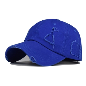 Close-up of distressed ripped details and raw edges on blue cotton baseball cap