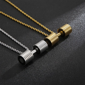 Close-up of barbell dumbbell pendants in gold and silver finishes on a black background