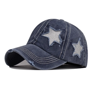 Dettaglio del cappello in denim blu slavato con toppa a stella d'argento e bordi sfrangiati