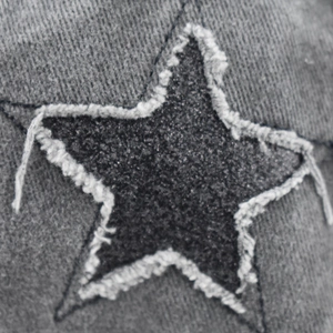 Dettaglio macro del cappellino in cotone lavato con stella e bordi sfrangiati vintage